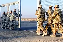 Soldats en uniformes beiges refermant une grille