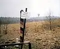 Un poteau ouest-allemand avec un panneau d'avertissement marque l'emplacement de la frontière