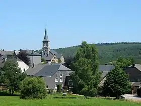 Paysage avec un édifice religieux, des bâtiments et une forêt.