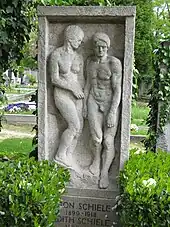 Photo couleur d'une sculpture de pierre rectangulaire avec un homme et une femme en haut-relief