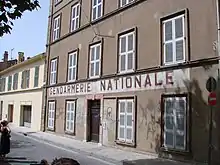 Un bâtiment de style provençal à l'abandon, les volets fermés, affichant sur la façade l'inscription « Gendarmerie nationale ».