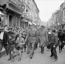 Accueilli par une foule enthousiaste, le général de Gaulle marchant dans les rues de Bayeux le 14 juin 1944.