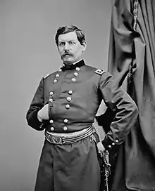 Photo of man with goatee and his right hand thrust into a dark military uniform