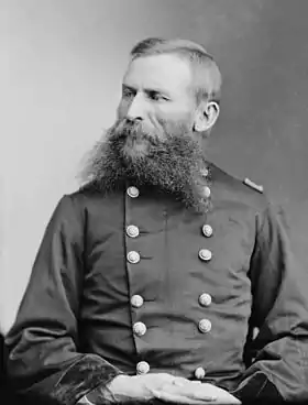Portrait noir et blanc d'un homme en tenue militaire portant une barbe fourchue.