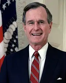 Photographie officielle du président des États-Unis, George H. W. Bush, derrière le drapeau national.