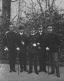 Photographie en noir et blanc montrant cinq hommes d'âges différents en uniformes militaires.