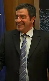 Photographie d'un homme souriant avec en arrière-plan le drapeau européen.