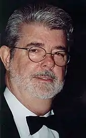 Homme portant des lunettes, une barbe et des cheveux gris.