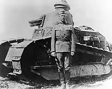 Patton en uniforme avec un calot devant un petit char