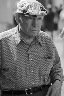photo noir et blanc d'un vieil homme en chemise, avec une casquette à carreaux