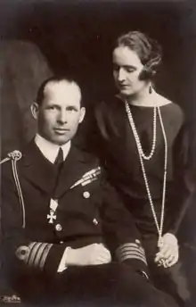 Photo noir et blanc d'un homme en tenue militaire assis, une femme debout à ses côtés.