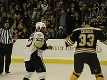 Photographie de Georges Laraque et Zdeno Chára prêts à se battre sous les yeux du public et d'un arbitre.