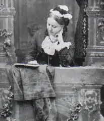 Daguerrotype de Georgina, penché sur un livre, cheveux relevés sous un bonnet blanc, robe noire, environ 40 ans, table avec draperies.