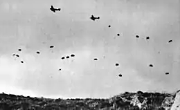photographie noir et blanc : des parachutistes tombent d'avions