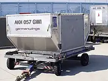 Photo en gros plan d'un conteneur métallique de taille moyenne positionné sur un chariot à roulettes.