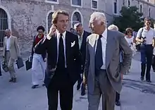 Photo de deux hommes en costume-cravate, discutant en ville
