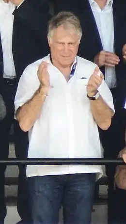 Un homme en chemise, avec un badge autour du cou, applaudit