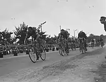 Photographie en noir et blanc montrant plusieurs cyclistes en course.