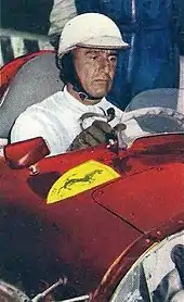 Photo de Giuseppe Farina au volant d'une voiture portant l'insigne de la Scuderia Ferrari et dépourvue de capot moteur.