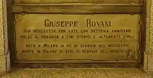 A marble gravestone on the wall of a crypt