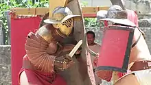 Gladiateur protégé par son bouclier et sa manica.