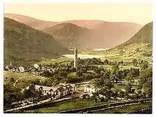 Carte postale ancienne présentant le village de Glendalough à la fin du XIXe siècle, dans un vallon vert avec un petit lac au fond
