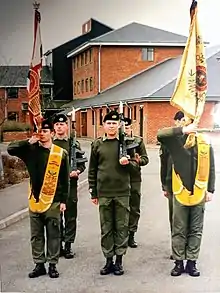 Six militaires portant deux drapeaux.