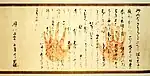 Texte japonais manuscrit avec deux empreintes de main en rouge.