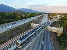 Rame de métro vue du ciel, au-dessus d'une autoroute.