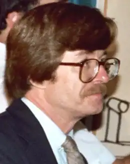 photo en couleur du visage en gros plan d'un homme portant moustaches et lunettes