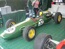 Photographie de la Lotus 25 vert foncé, vue de trois-quarts, dans un stand d'exposition.