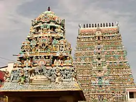 Photo couleur de deux tours d’un temple hindou, surchargées de frises colorées superposées. Un ciel nuageux en arrière-plan.