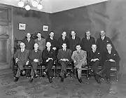 Photographie noir et blanc de quatorze hommes répartis sur deux rangées.