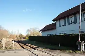 Quais (dont un est recouvert par la végétation), voie unique et ancien bâtiment voyageurs, vus depuis le passage à niveau voisin.