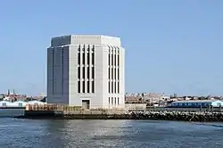 Vue d'un bâtiment octogonal en béton, sur une île.