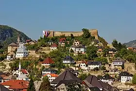 Une ville surplombée par une colline sur laquelle se trouve une forteresse médiévale.