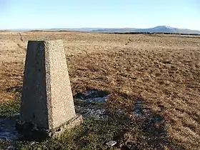 Vue de la borne géodésique au sommet avec, en arrière-plan, le mur marquant la limite de comté et Whernside.