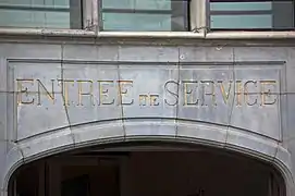 Inscription « entrée de service » au-dessus de la porte centrale de l'annexe.