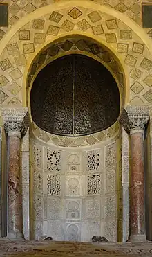 Photographie du mihrab de la Grande Mosquée de Kairouan, dont l'état actuel, daté de 862-863, est du au prince aghlabide Abou Ibrahim Ahmed. Il s'agit d'une niche soigneusement décorée, aménagée à peu près au milieu du mur méridional, dit de la qibla, de la salle de prière.