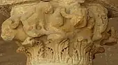 Photographie d'un chapiteau en pierre à figures animales, localisé à l'intérieur du portique occidental de la cour. Il est orné de bustes de bœuf.