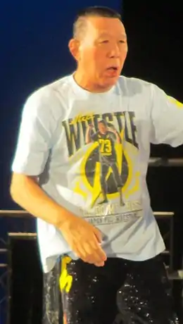 Un homme brun portant un t-shirt gris avec marqué dessus le mot Wrestle.