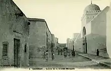 Photographie d'époque, vers 1900, montrant la façade occidentale de la Grande Mosquée de Kairouan. Les façades de l'édifice étaient entièrement badigeonnées à la chaux, avant les restaurations des années 1960.