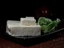 photographie d'une tranche d'un fromage blanc et de feuilles vertes
