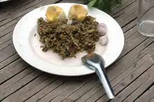 Photographie d'une assiette de viande d'iguane cuite avec des œufs d'iguane cuisinés en arrière-plan.