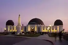 Observatoire blanc avec trois coupoles noires sur son toit. Il y a également une petite tour blanche à droite de l'observatoire.