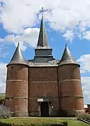 Façade de l'église avec ses deux tours fortifiées symétriques percées de meurtrières. Le  clocher octogonal se situe au-dessus du porche.