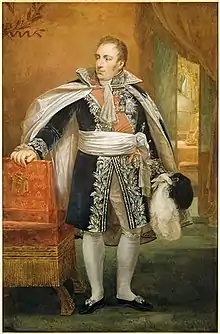 Portrait en pied d'un dignitaire du Premier Empire, tête tournée vers la gauche, vêtu d'un habit richement décoré et tenant d'une main un chapeau orné de plumes blanches.