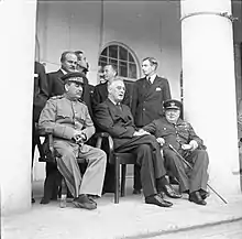 Joseph Staline, Franklin D. Roosevelt et Winston Churchill, assis au premier plan. Des membres de leurs gouvernements se tiennent debout à l'arrière-plan.