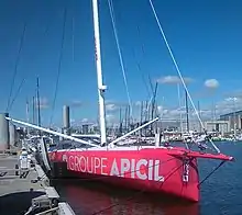 Voilier rouge et amarré au ponton, vu de trois quarts face.