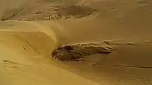 Un amoncellement de sable presque vertical, avec plein d'ondulations venant du vent.